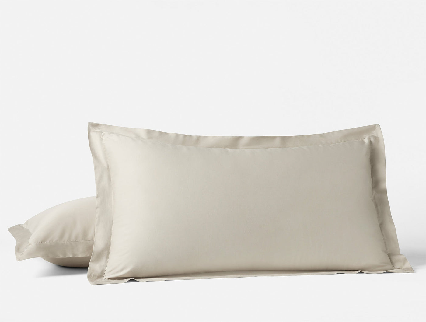 Two ivory Coyuchi Cloud Soft Sateen pillow shams stacked, showing tailored flange edge detail.