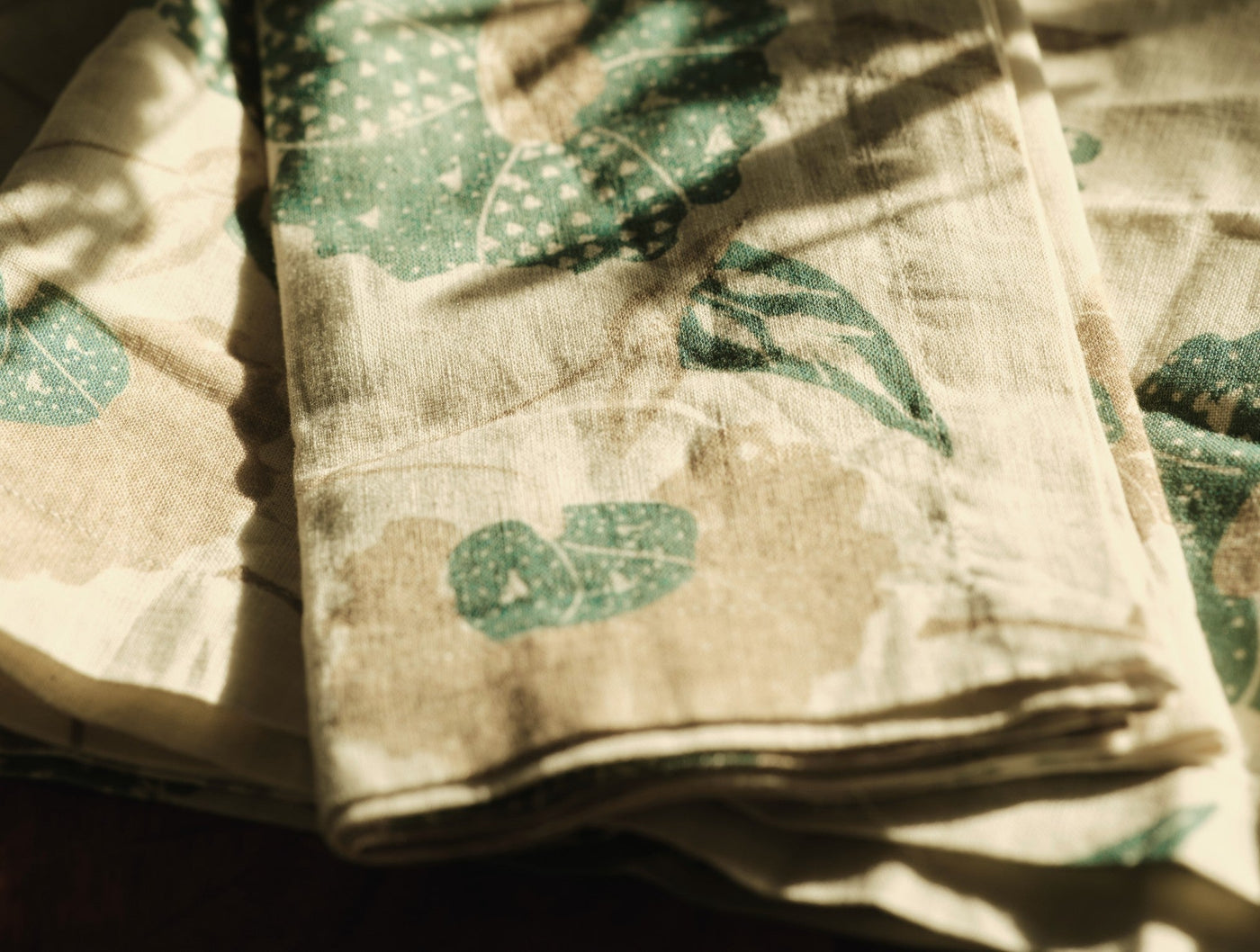Close-up of Coyuchi Aurora Print table runner in natural linen with sage green botanical print.