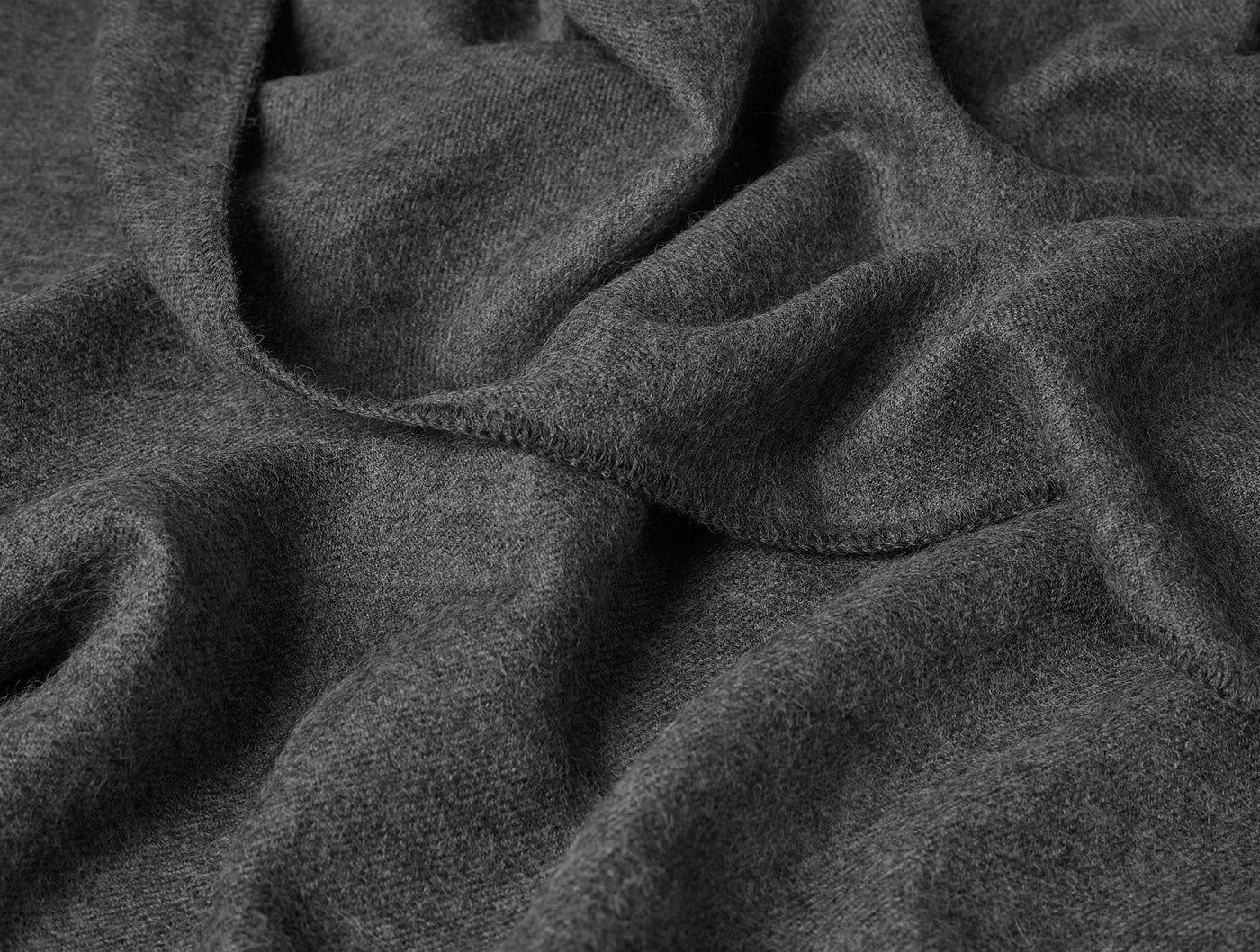Close-up of draped charcoal Coyuchi Pacaya Baby Alpaca blanket showing soft brushed texture.