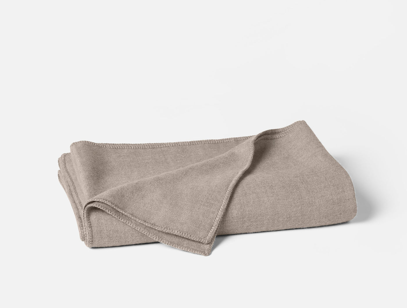 Folded oatmeal Coyuchi Pacaya blanket showing bound edge detail on white background.