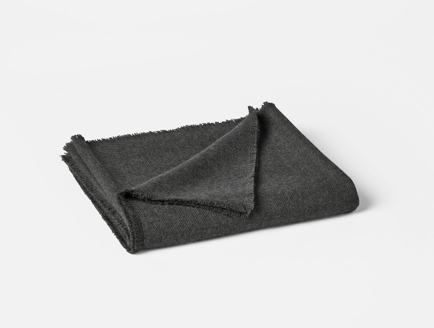 Folded charcoal alpaca throw with frayed hem detail, shot against white background.