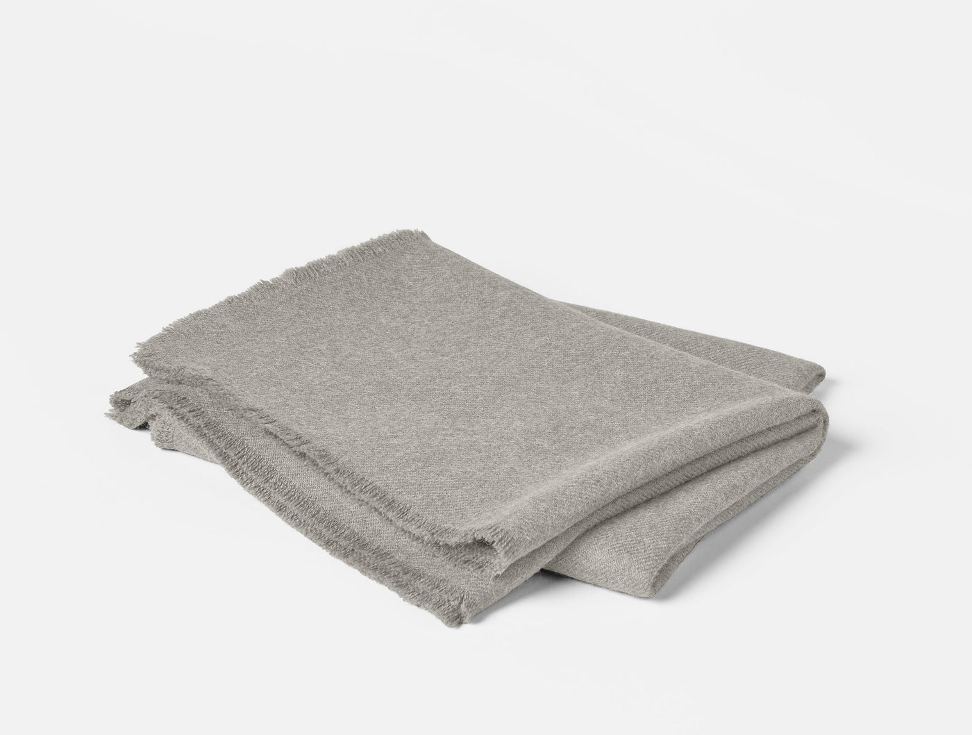 Folded stone grey alpaca throw with fringe trim, shown from above at a slight angle.
