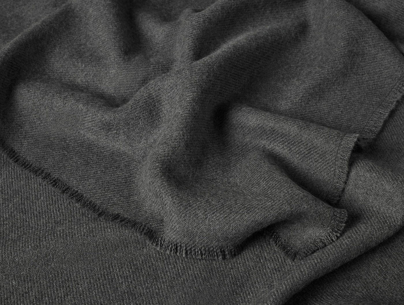 Close-up of charcoal Coyuchi Pacaya Baby Alpaca throw showing soft drape and blanket-stitch hem.