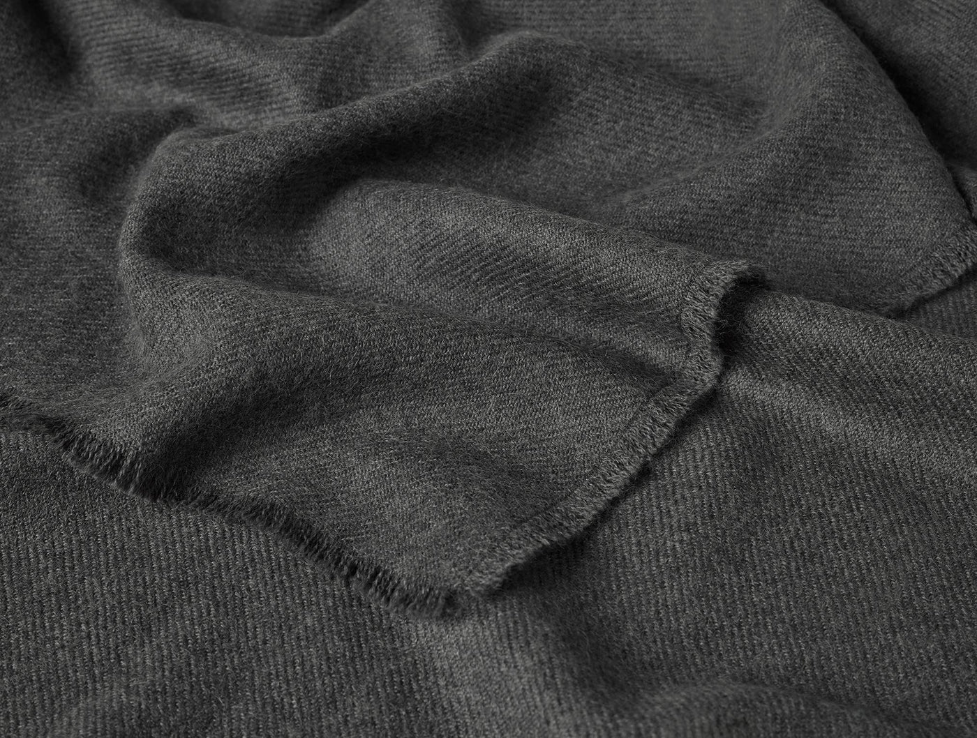 Close-up of charcoal Coyuchi Pacaya throw's fringed hem and soft alpaca weave texture.