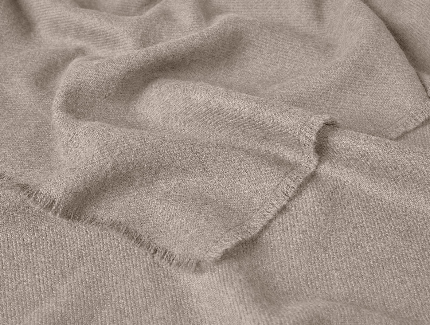 Close-up of fringed hem on a draped taupe Coyuchi Pacaya Baby Alpaca throw.