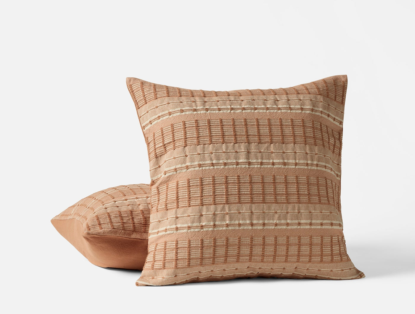 Coyuchi Sea Ridge pillows stacked, terracotta with woven stripe texture detail.