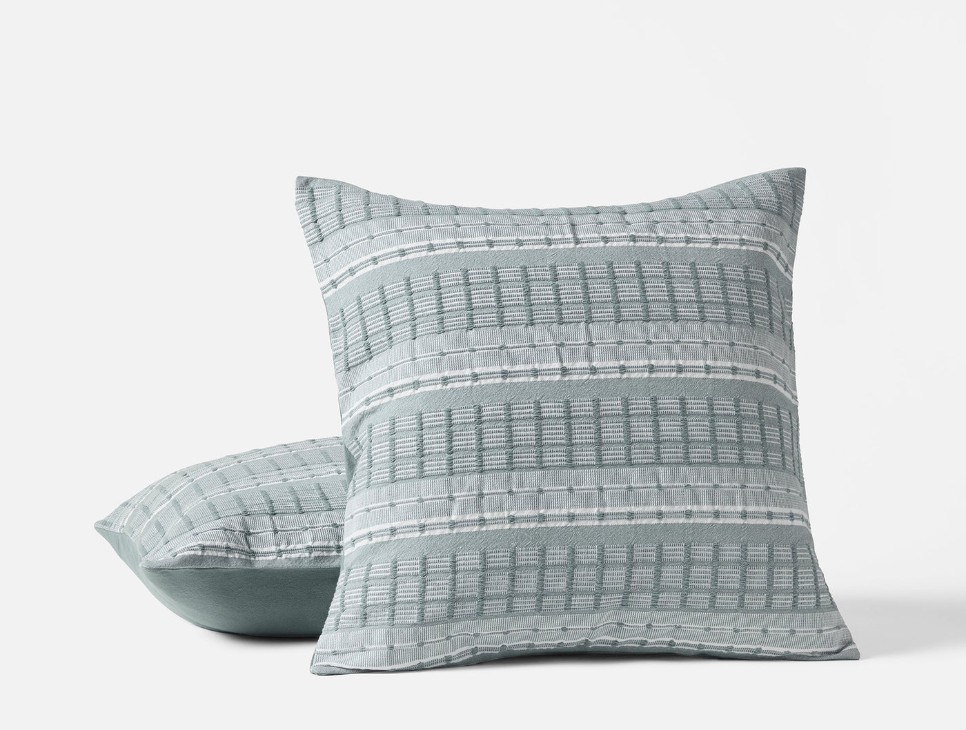 Coyuchi Sea Ridge pillow covers in sage, showing woven grid stripe pattern on stacked pair.