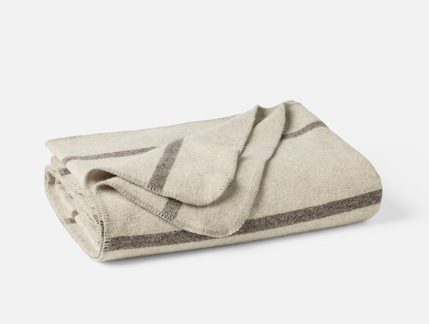 Folded ivory wool blanket with charcoal stripe border detail along edges.