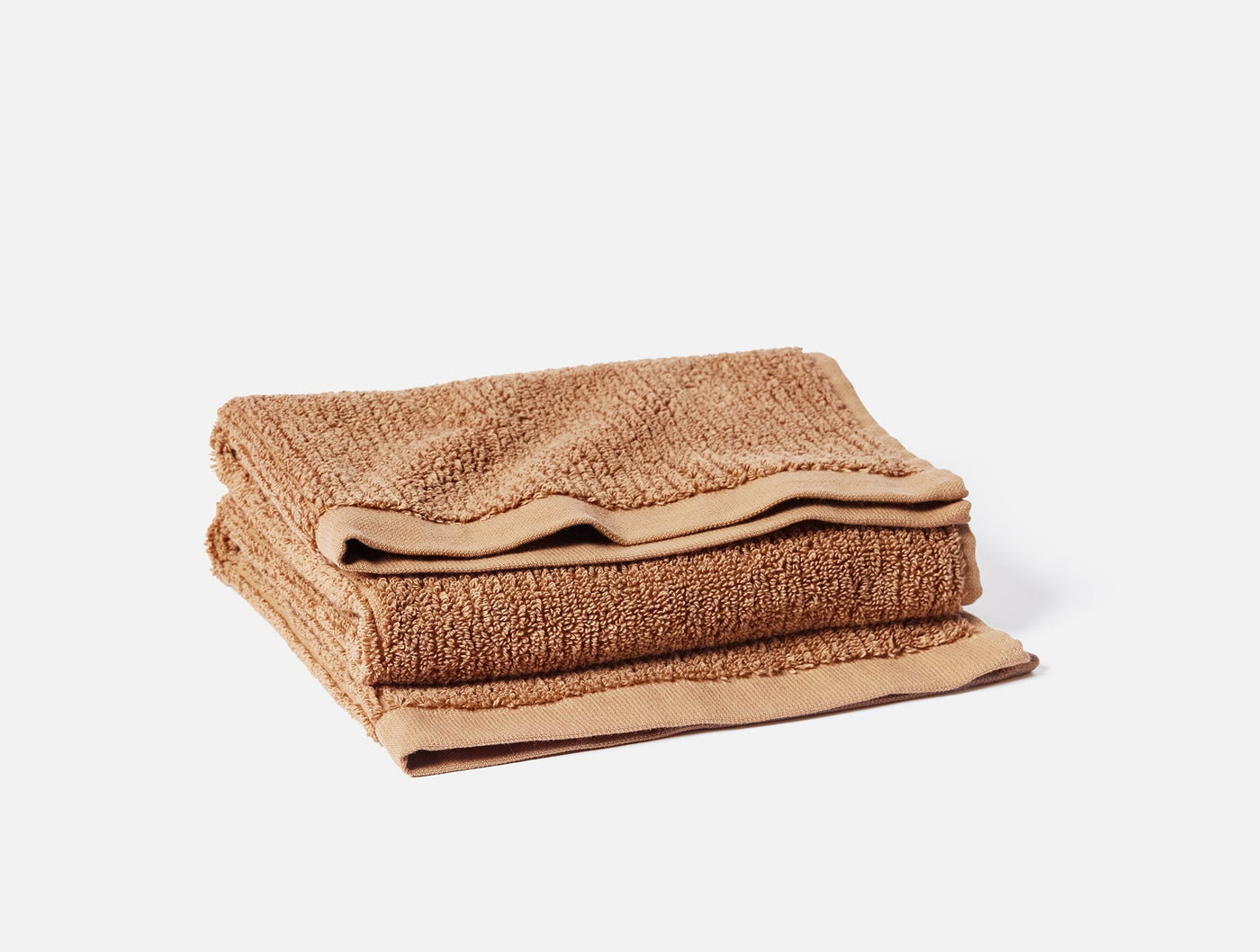Close-up of folded Coyuchi Temescal Ribbed 6-piece towel set in warm camel tone.