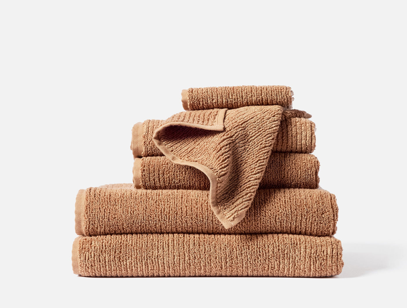 Coyuchi Temescal Ribbed towel set stacked in warm terracotta, ribbed texture visible.