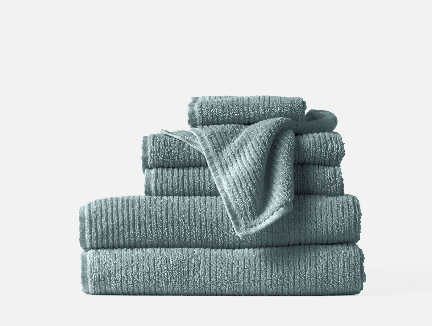 Close-up of stacked Coyuchi Temescal Ribbed towel set in muted teal with ribbed texture detail.
