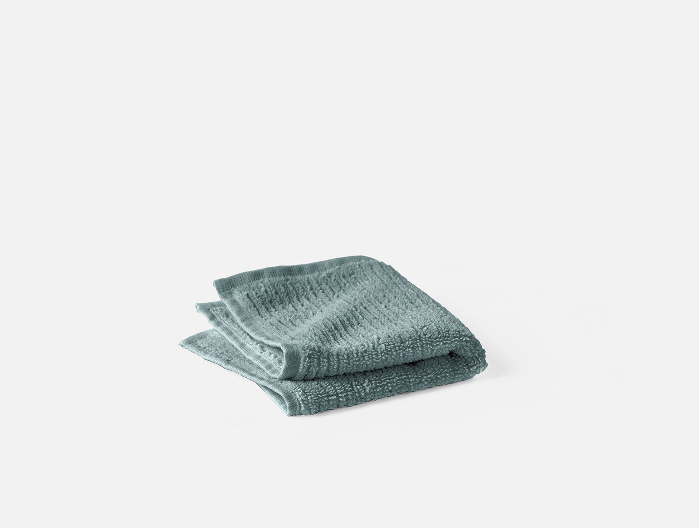 Coyuchi Temescal wash cloth folded, sage green ribbed texture visible on edges.