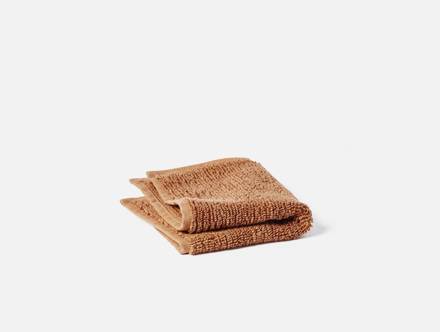 Folded canyon-hued ribbed cotton washcloth, compact square stack on white background.