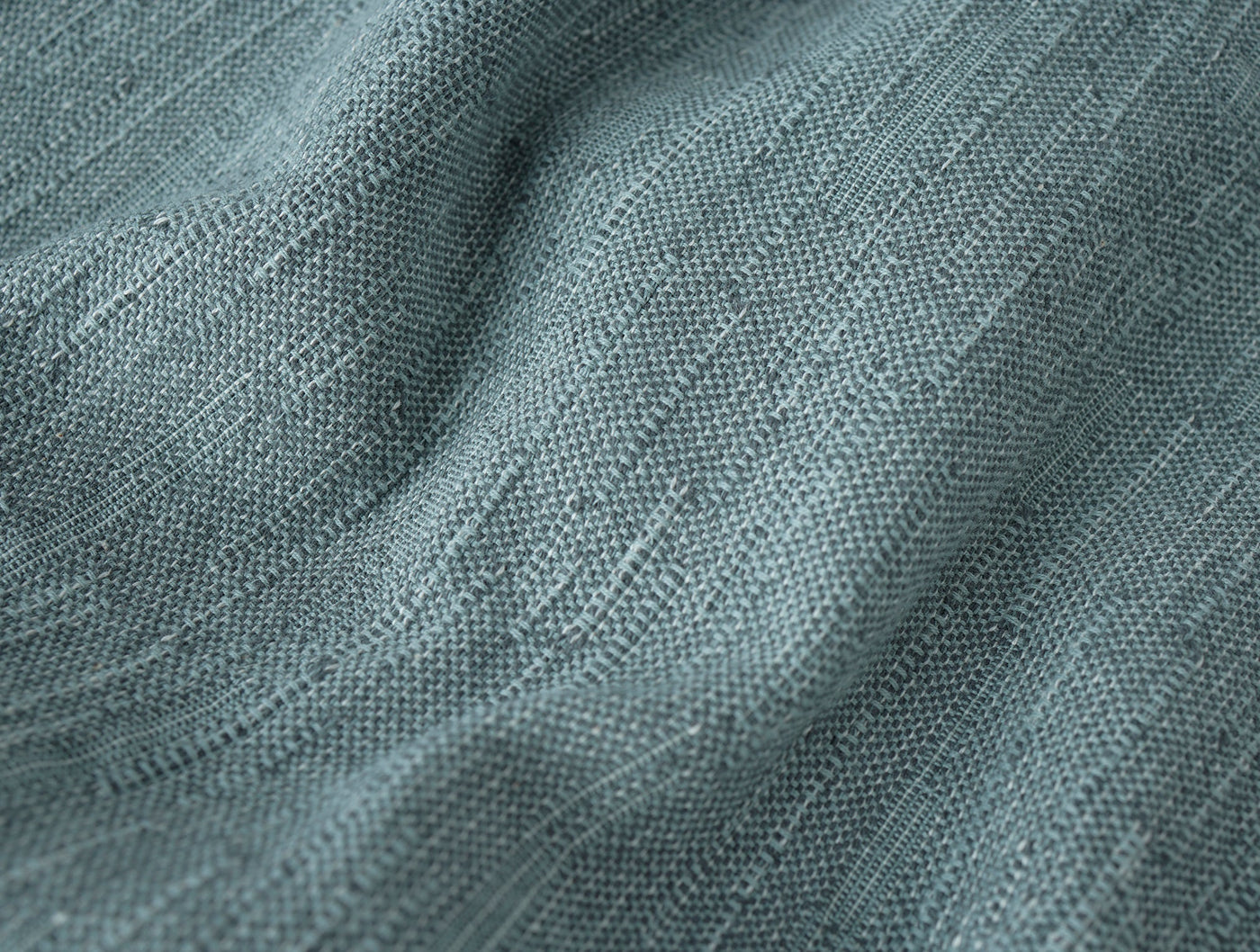 Close-up of draped teal-blue linen weave showing subtle texture and natural slub detail.