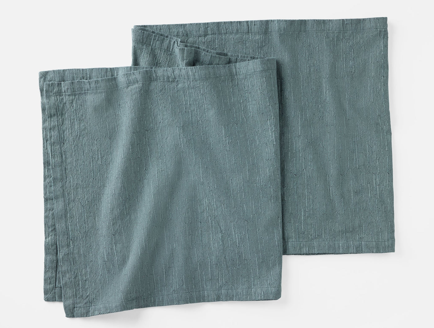 Pair of slate blue linen napkins folded flat, showing subtle woven texture.
