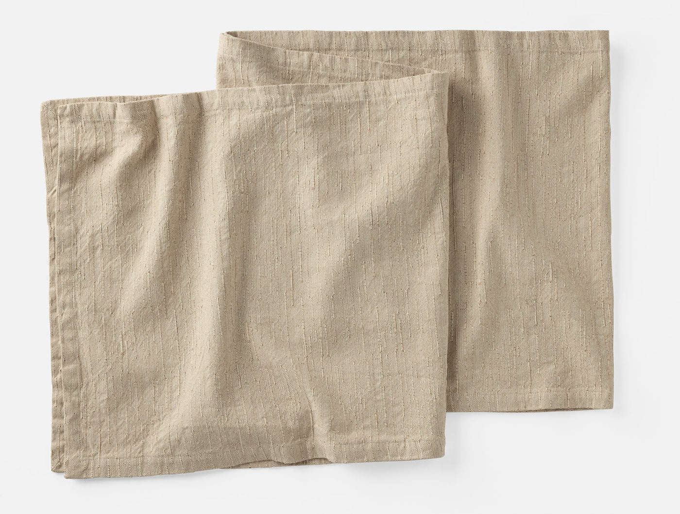 Two Coyuchi Toro Canyon napkins in natural linen, slightly overlapping on white background.