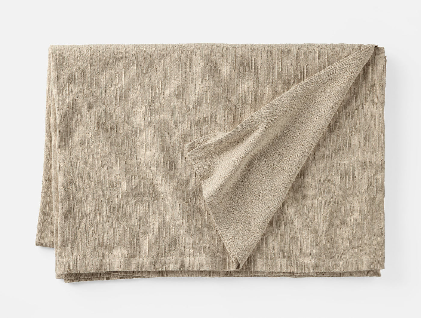 Corner fold detail revealing ivory underside of Coyuchi Toro Canyon linen tablecloth in oat.