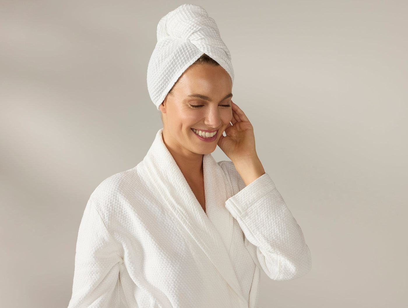 Woman wearing Coyuchi white waffle hair wrap as towel turban, paired with matching robe.