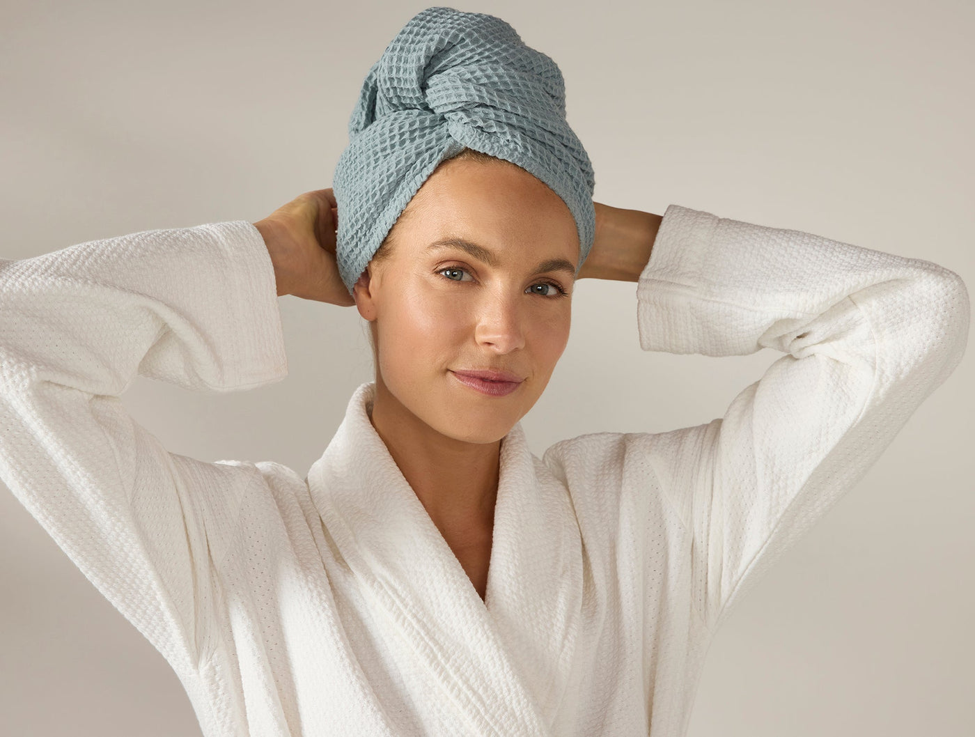 Woman wearing Coyuchi waffle hair wrap in slate blue, paired with white waffle robe.