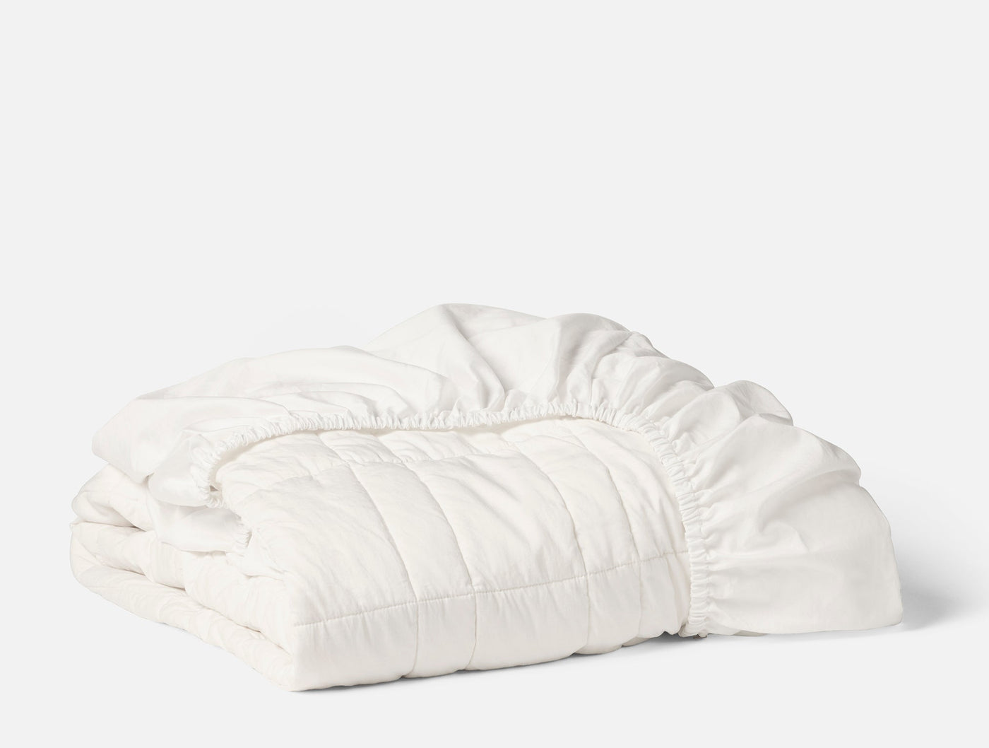 Coyuchi Washable Wool Filled Mattress Pad in white, folded to show quilted texture.