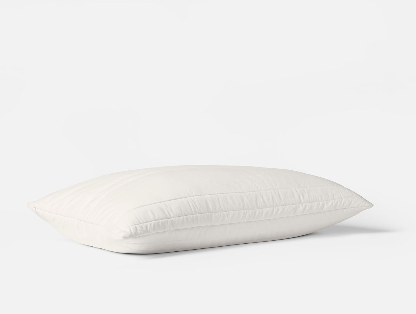 Coyuchi Washable Wool Filled pillow protector in white, shown plump on light background.