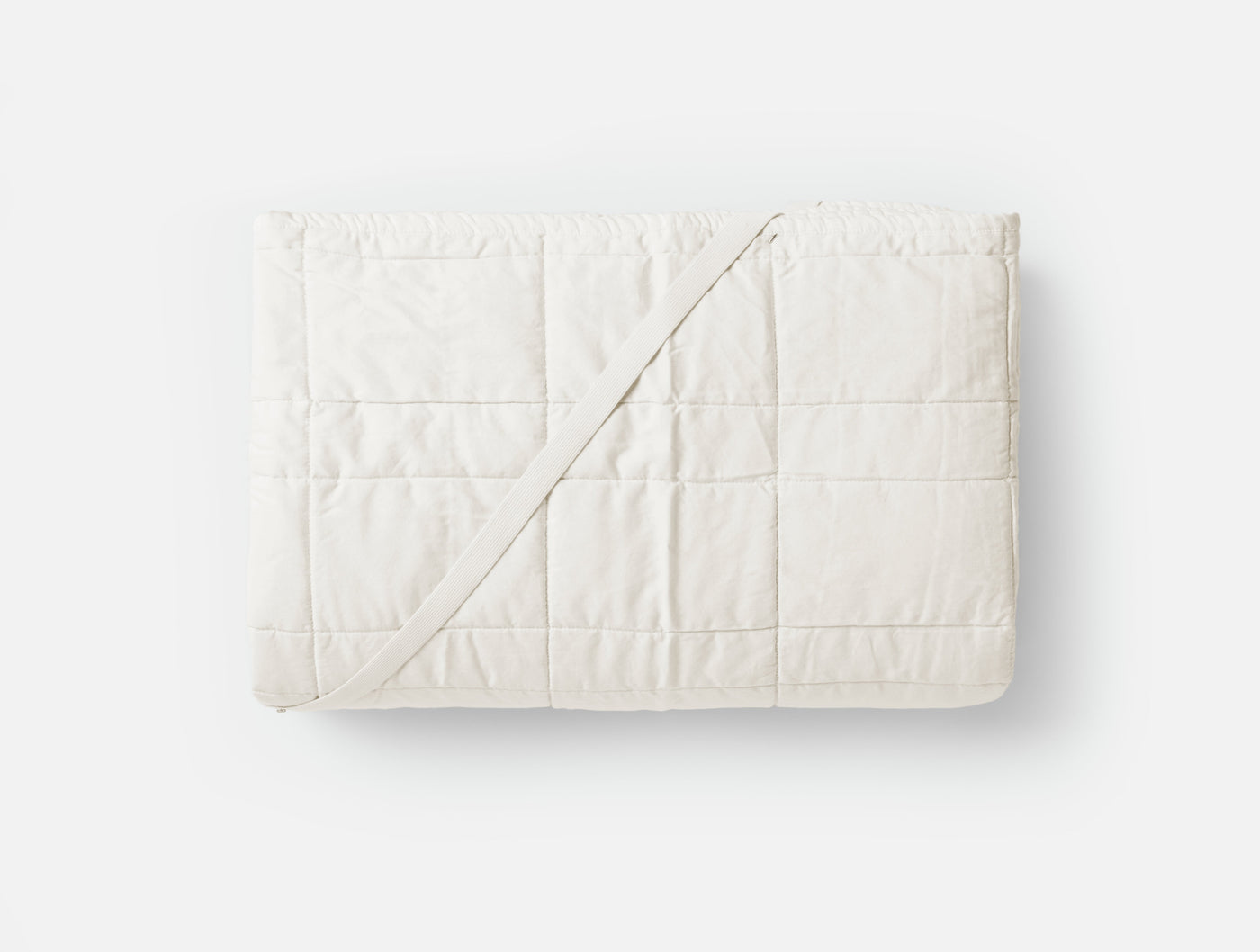Coyuchi Washable Wool Mattress Topper folded flat, ivory quilted cotton, grid stitching detail.