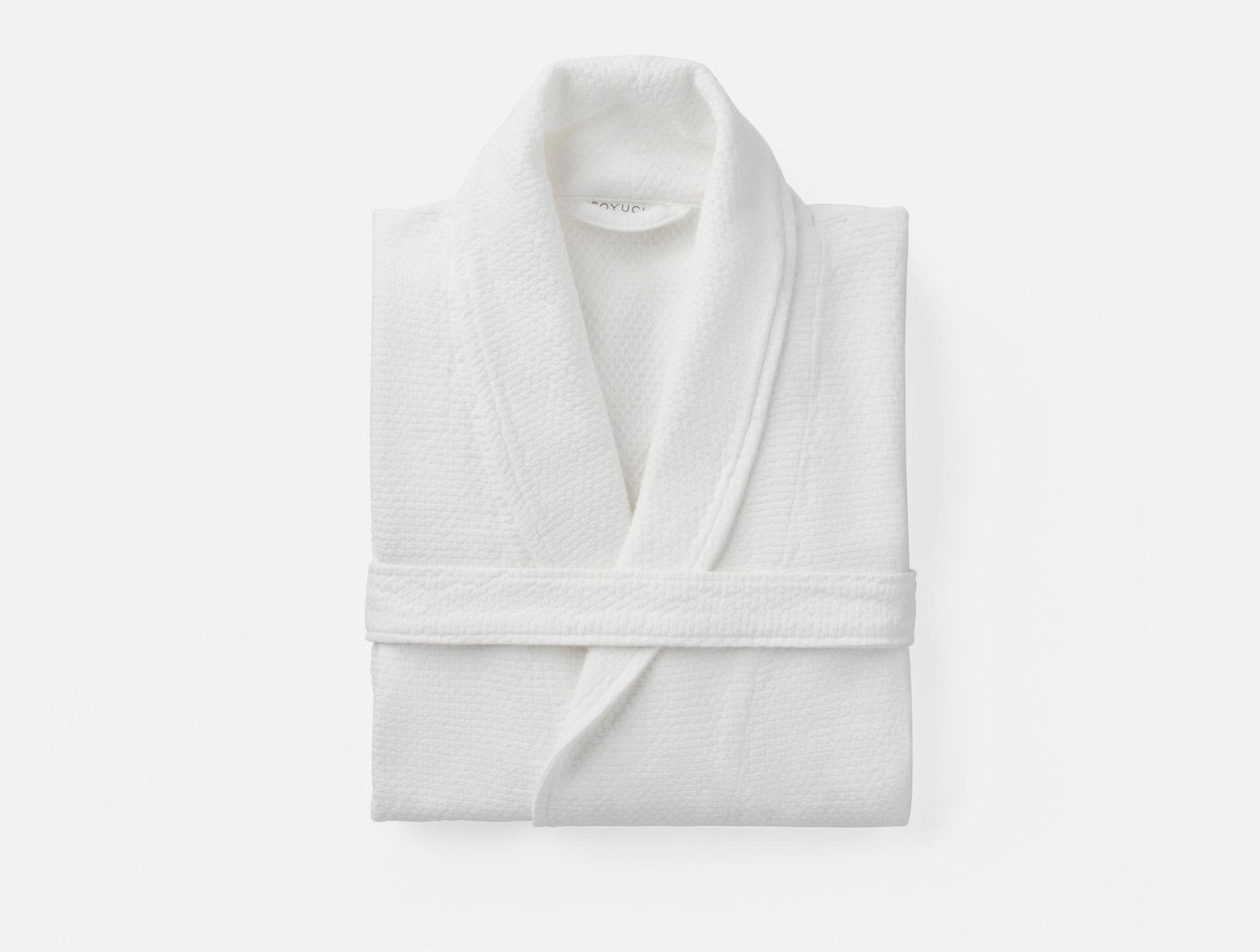 Coyuchi Adriatic robe folded flat, white waffle-weave cotton with shawl collar.