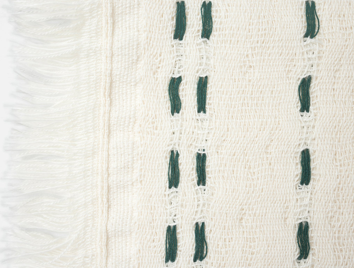 Close-up of ivory woven hand towel with forest green dash embroidery and fringe edge.