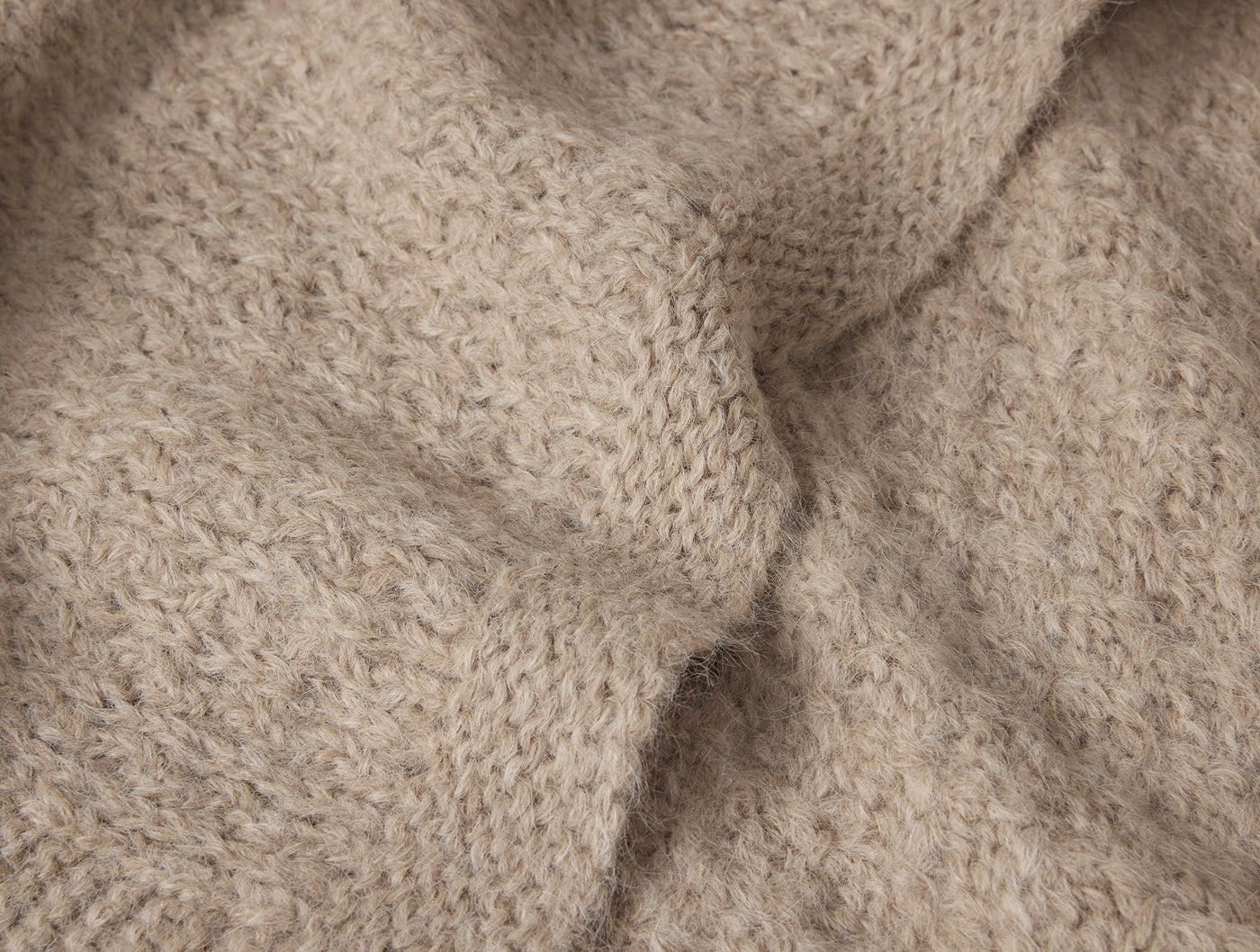 Close-up of Coyuchi Alpamayo throw's oatmeal suri alpaca knit texture with soft draping folds.