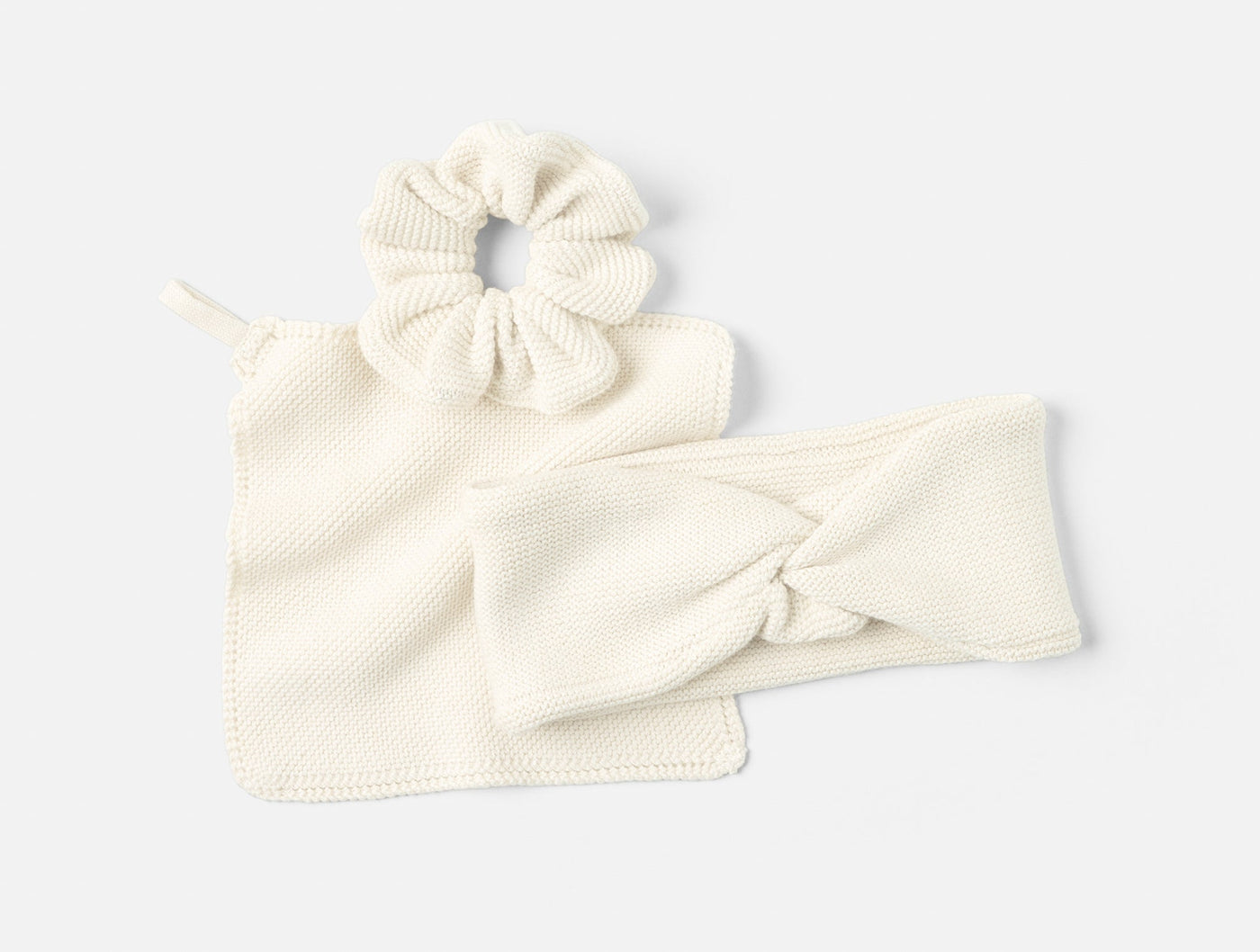 Coyuchi Bare knit gift set in ivory: scrunchie, headband, and washcloth laid flat.