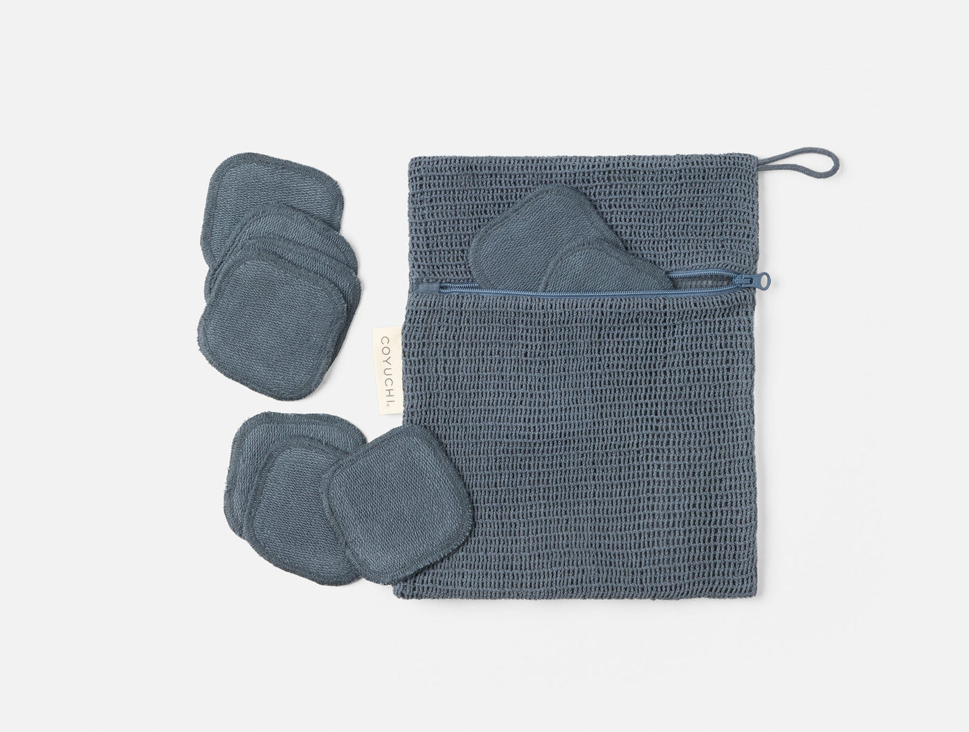 Coyuchi Bare makeup pads in slate blue with waffle-weave storage pouch, flat lay.
