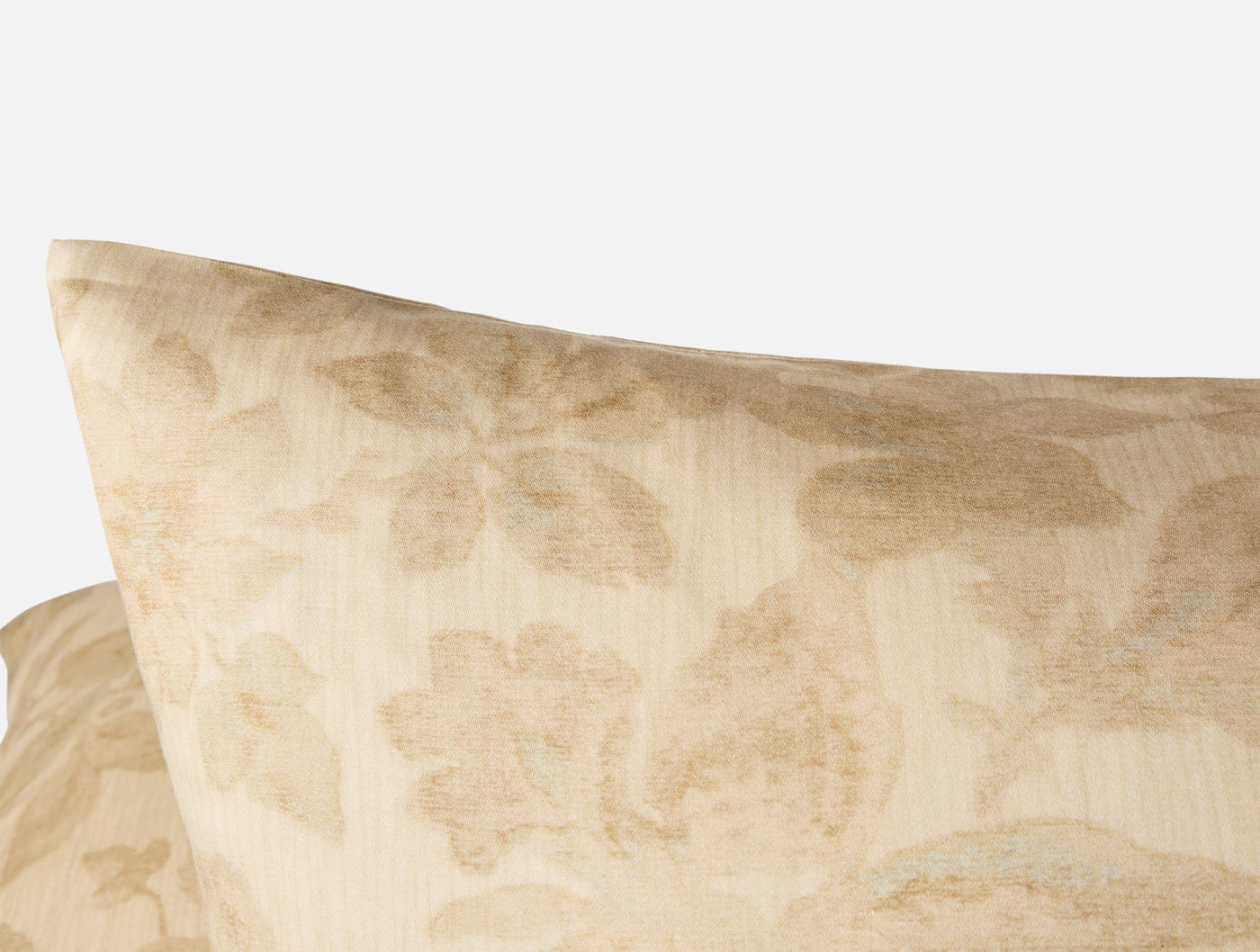 Close-up of Coyuchi Camellia Print sham corner, ivory damask floral pattern on textured fabric.