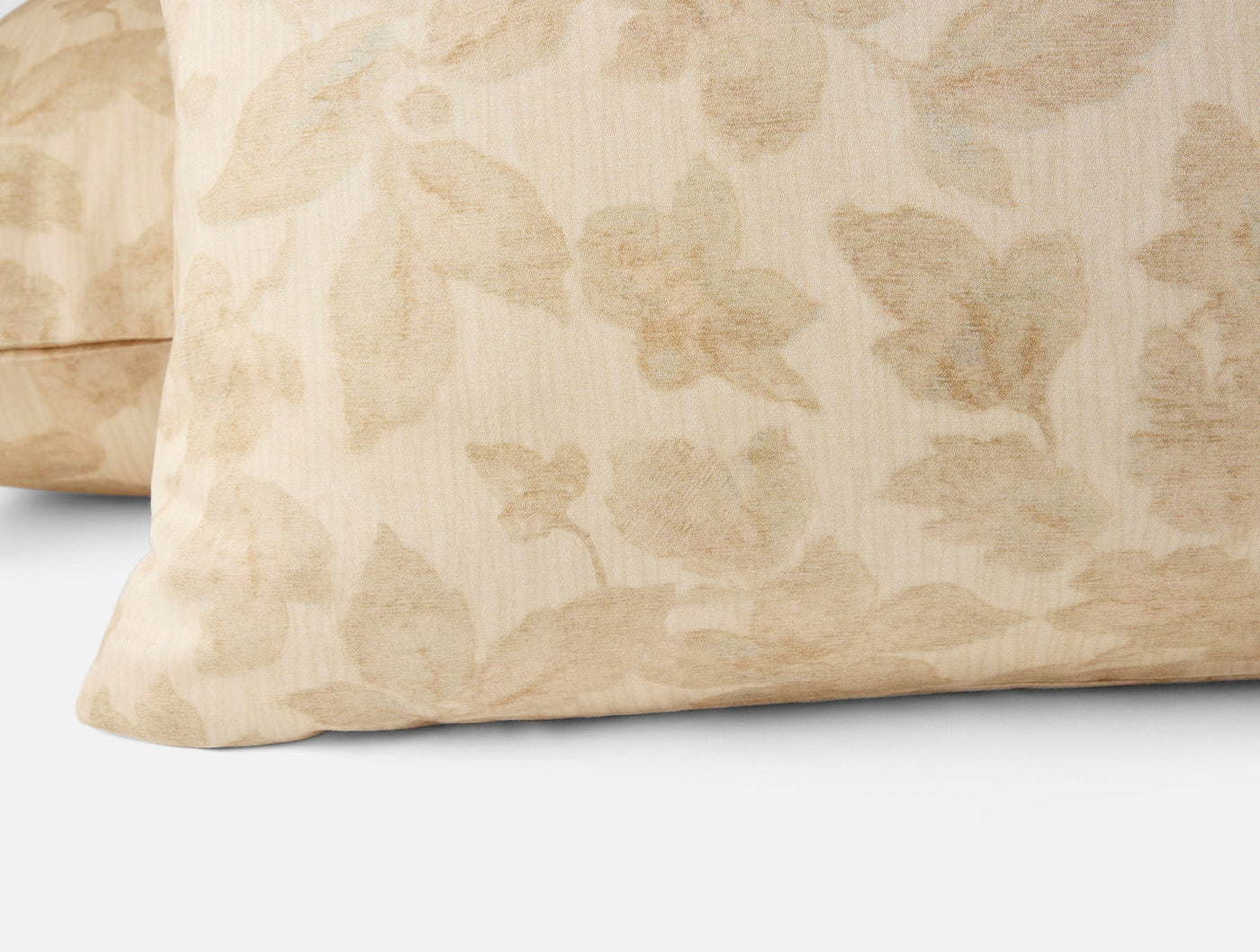 Close-up of two Coyuchi Camellia Print shams in champagne with tone-on-tone floral motif.