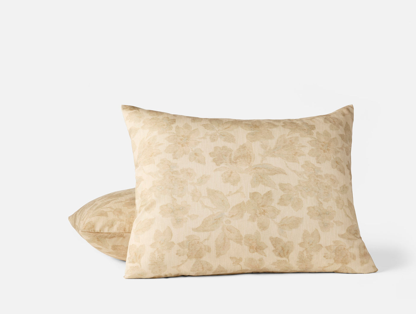 Close-up of two Coyuchi Camellia Print shams in champagne with tone-on-tone floral pattern.