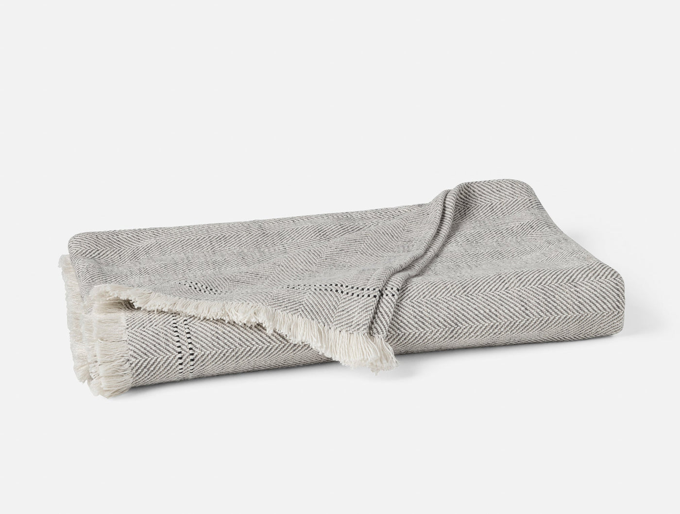 Coyuchi Canyon throw in grey herringbone weave with ivory fringe trim, folded flat.