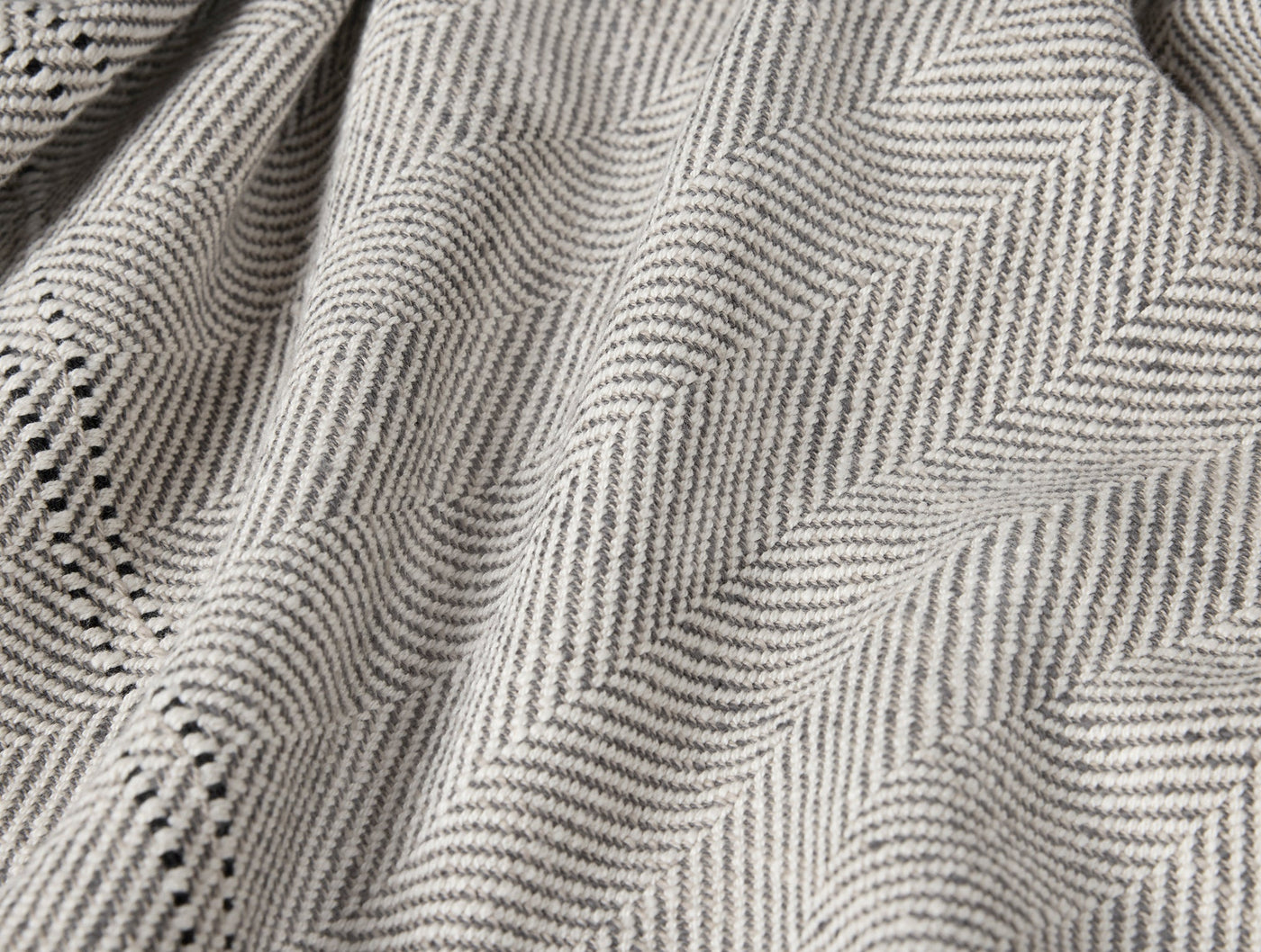 Close-up of Coyuchi Canyon throw herringbone weave in soft grey tones.