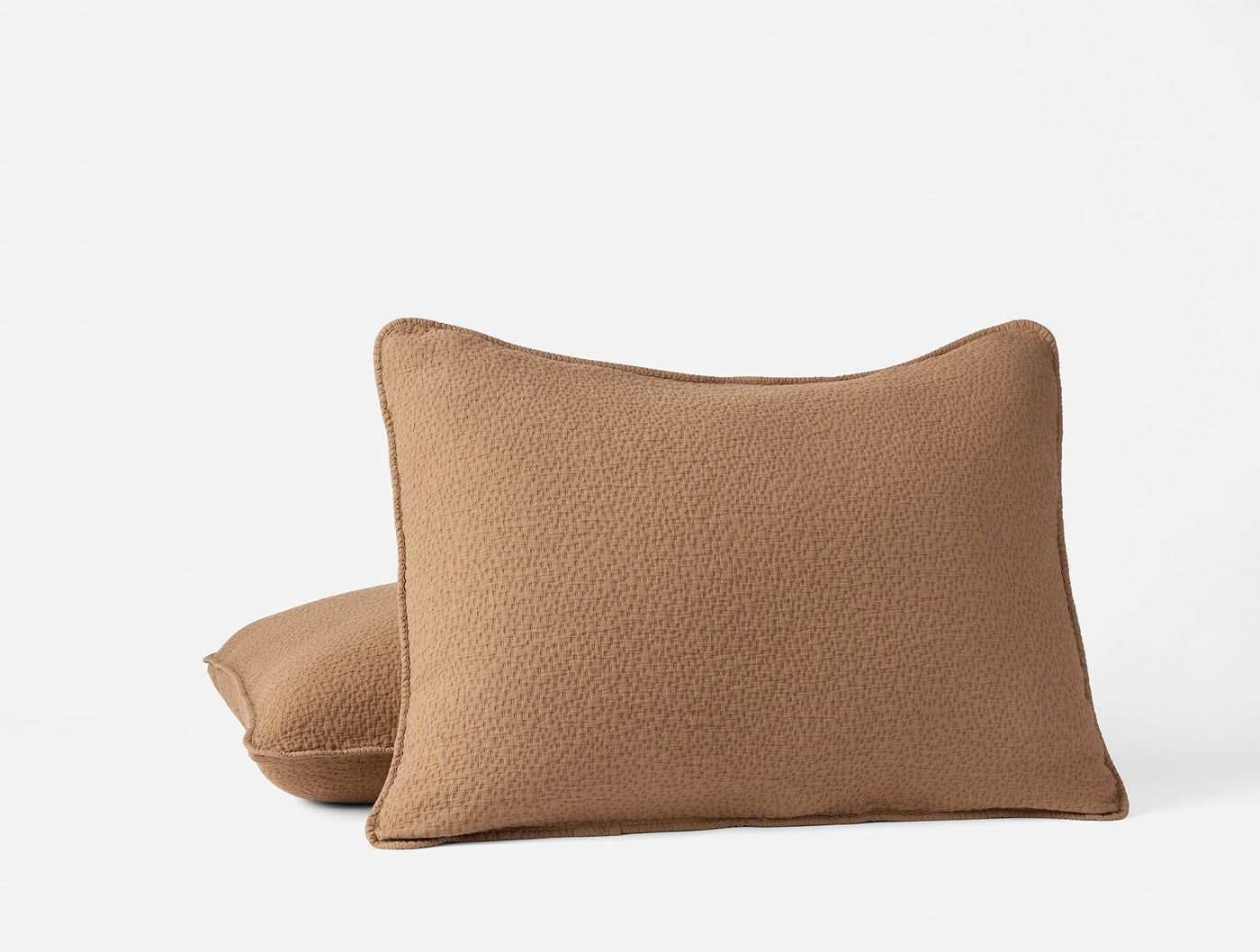 Two Coyuchi Cascade Matelassé shams in camel, textured boucle fabric, stacked on white background.