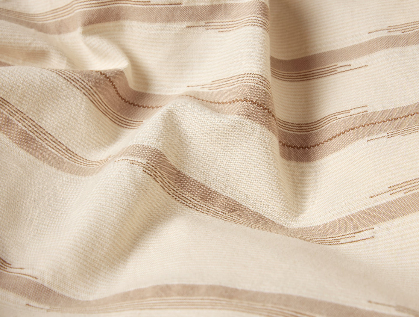 Close-up of ivory fabric with woven taupe stripe and zigzag embroidery detail.