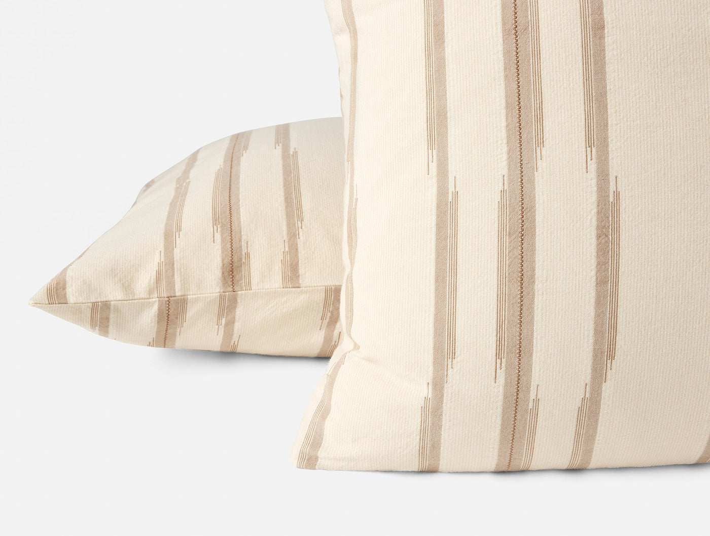 Two ivory Coyuchi Cazadero Stripe shams stacked, showing brushstroke tan stripe detail.