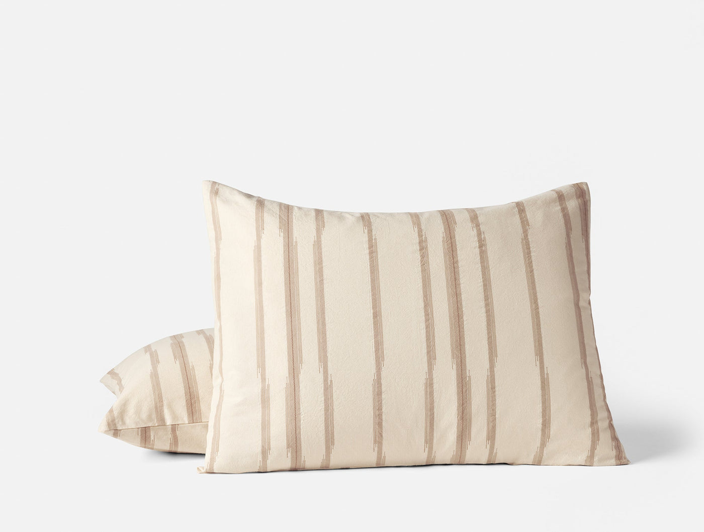 Close-up of Cazadero Stripe shams in ivory with warm tan vertical brushstroke stripes.