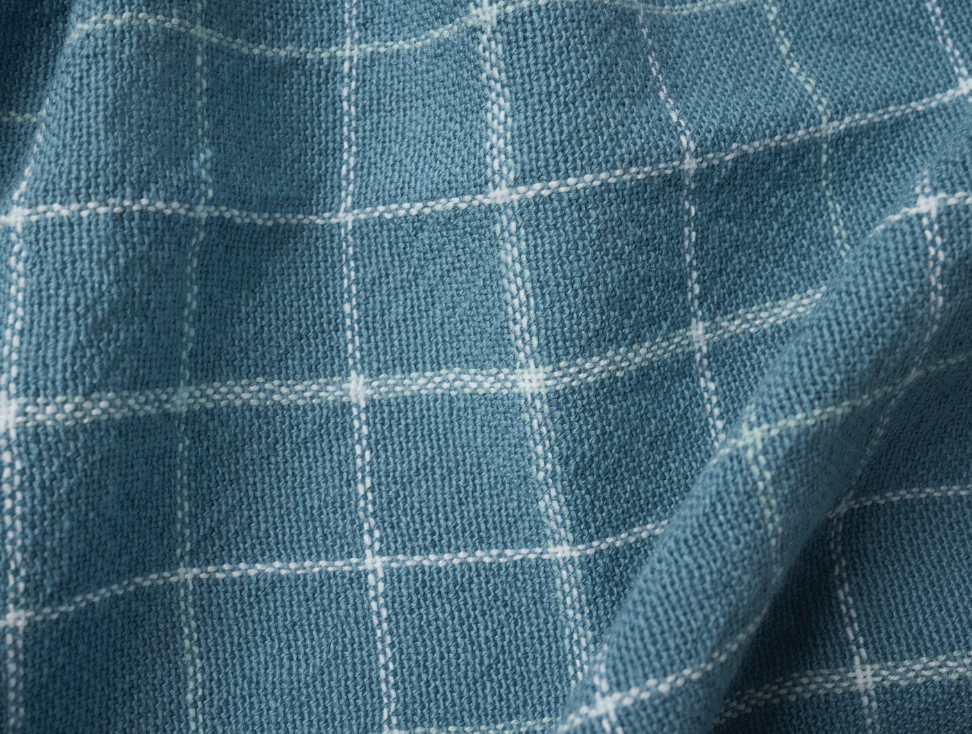Close-up of Coyuchi Clarendon kitchen towel in slate blue with white windowpane grid weave.