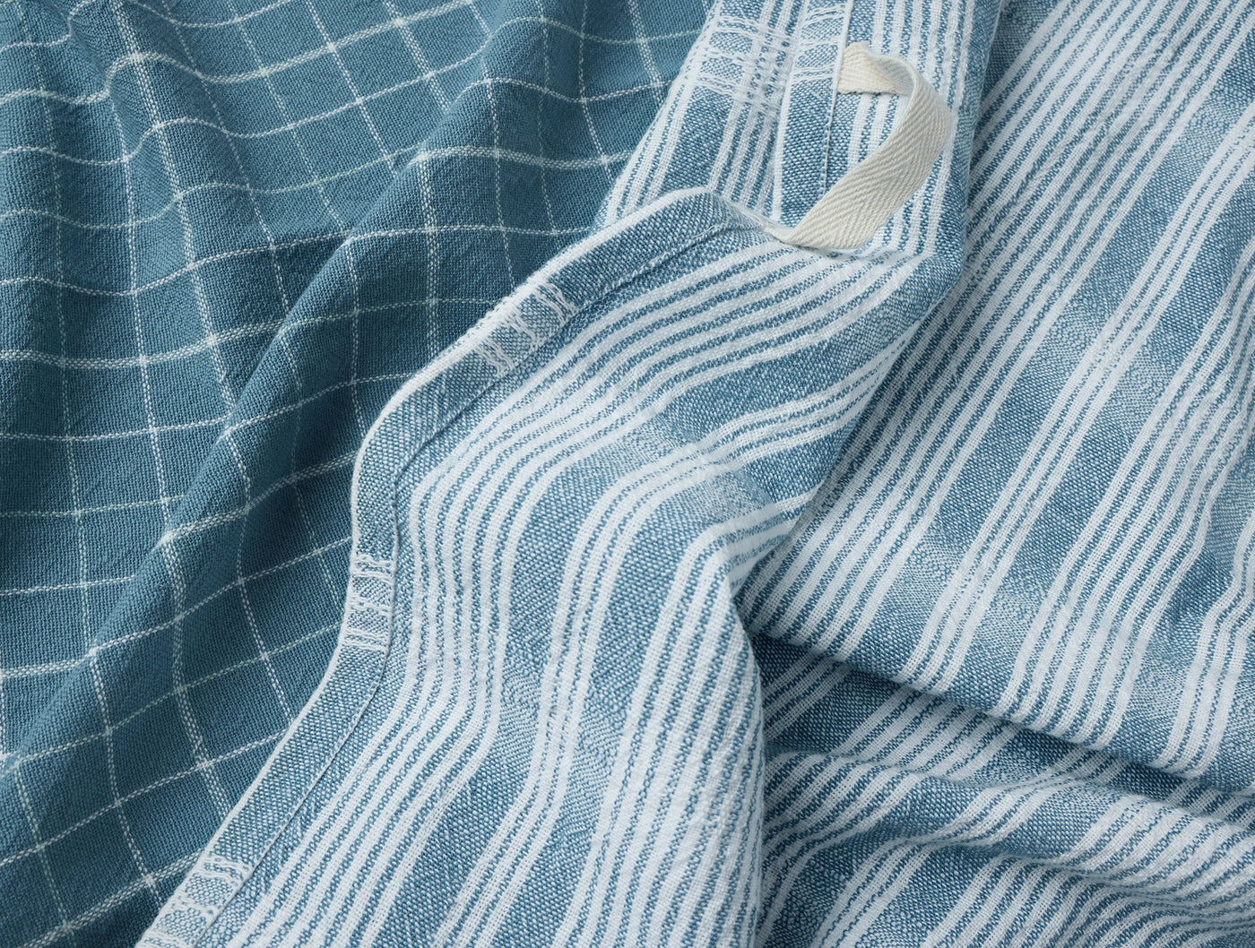 Close-up of Coyuchi Clarendon kitchen towel showing teal check and stripe weave patterns.