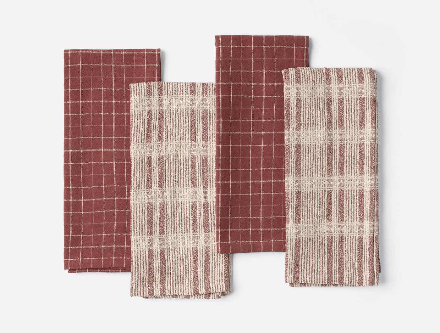 Coyuchi Clarendon kitchen towels in crimson, four folded showing grid and plaid weave patterns.