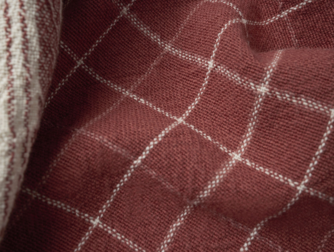 Close-up of Coyuchi Clarendon kitchen towel in deep burgundy with ivory windowpane grid stitching.