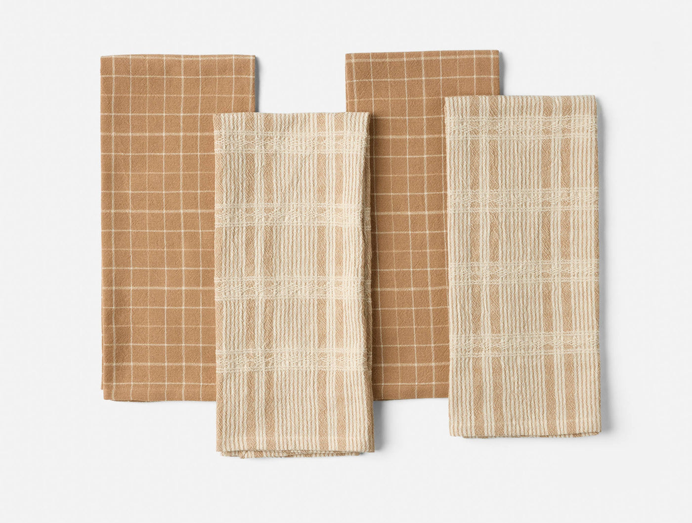 Coyuchi Clarendon kitchen towels in caramel and ivory plaid patterns, set of four folded flat.