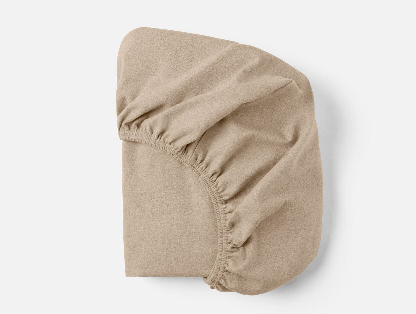 Underside view of a sand fitted sheet showing elasticized corners and hem detail.
