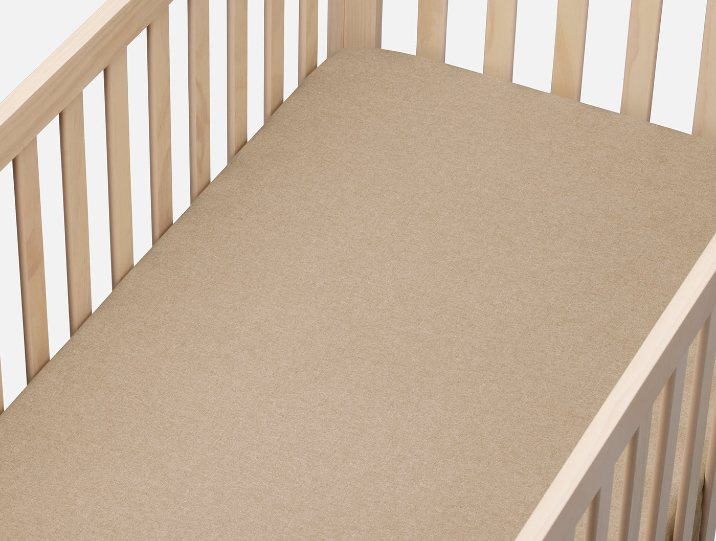 Coyuchi Cloud Brushed Flannel fitted sheet in warm tan fitted to a natural wood crib.