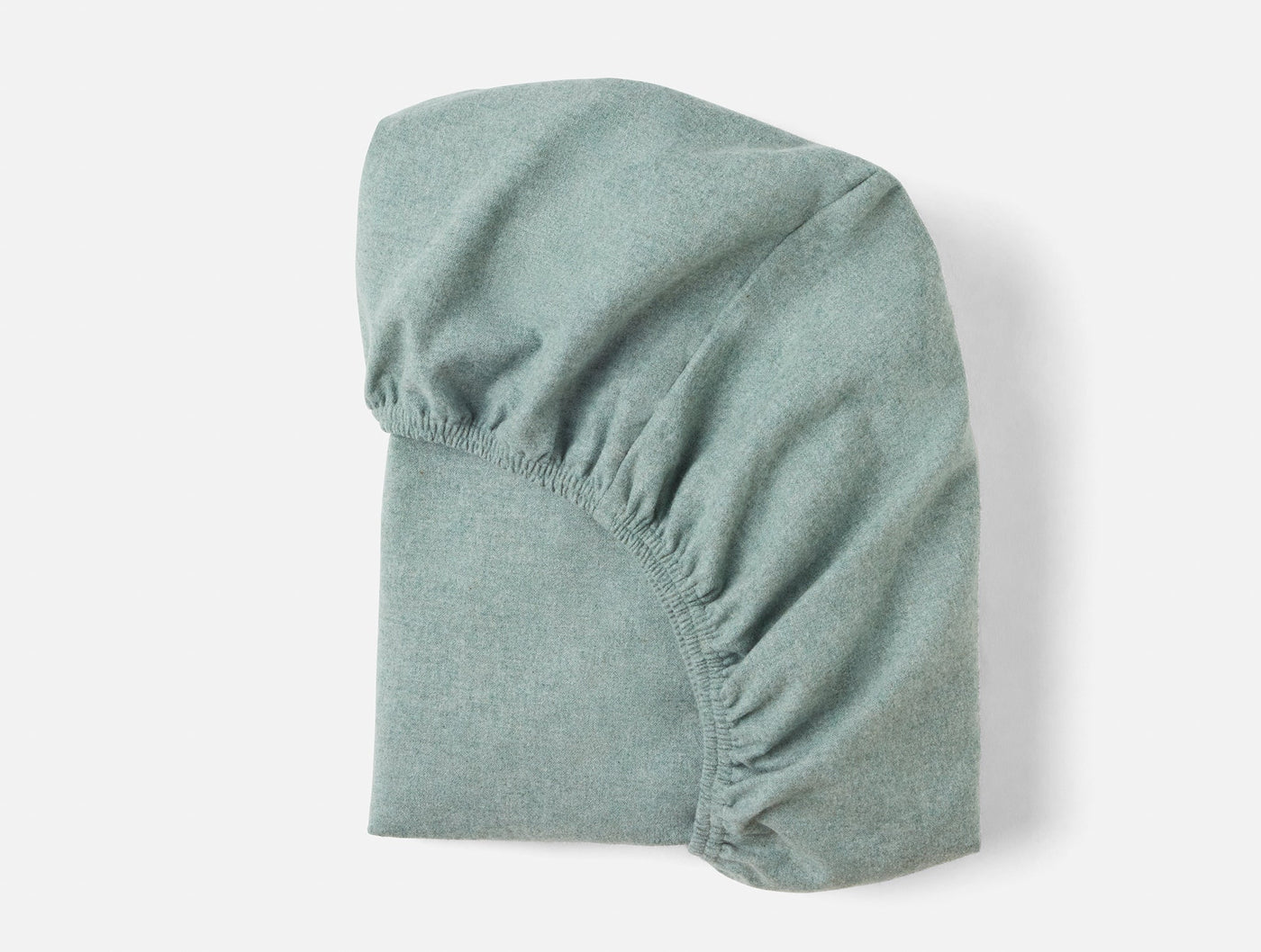 Coyuchi Cloud Brushed Flannel fitted sheet in sage green, folded to show elasticized corners.