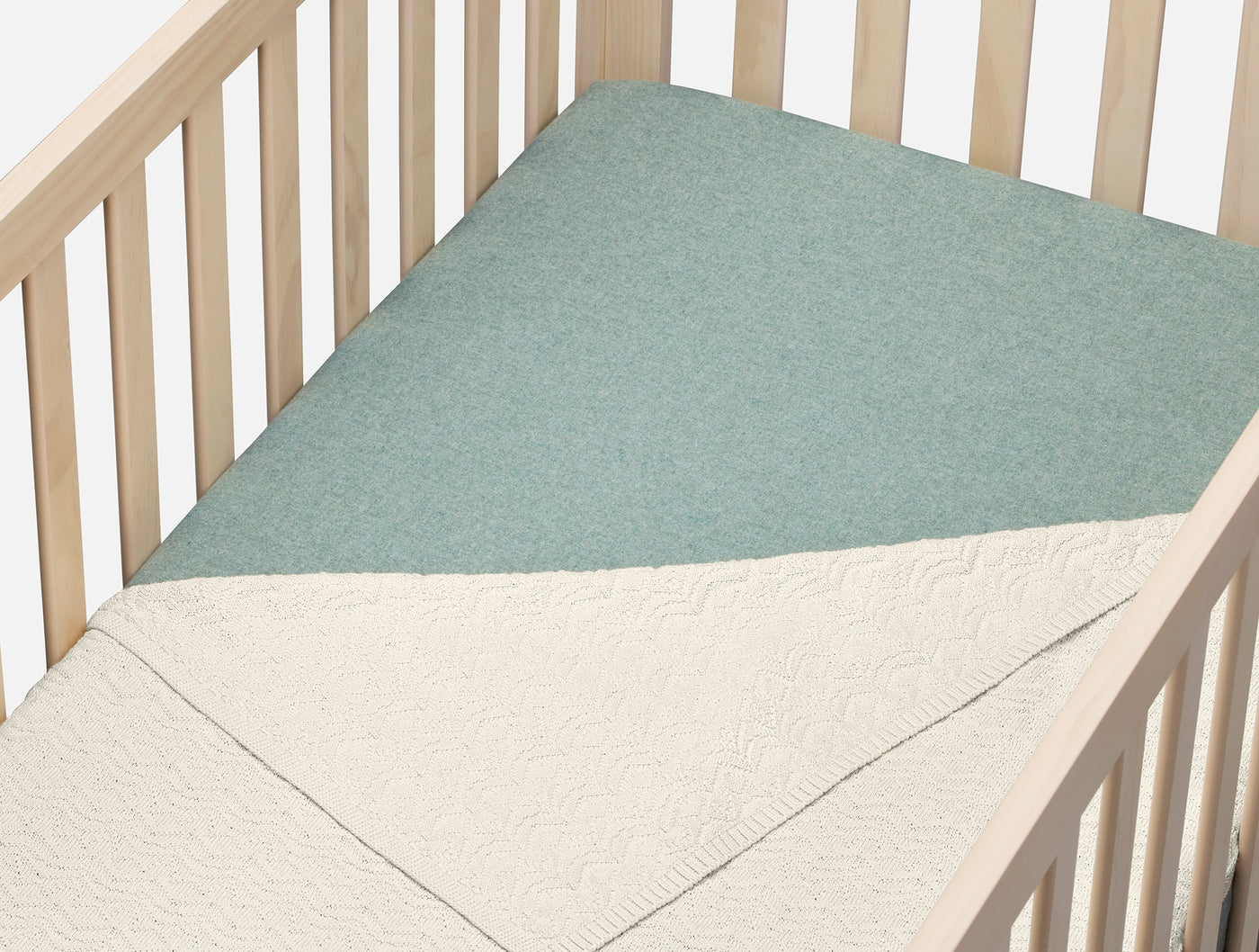 Sage flannel fitted sheet on a crib mattress, paired with an ivory quilted blanket.