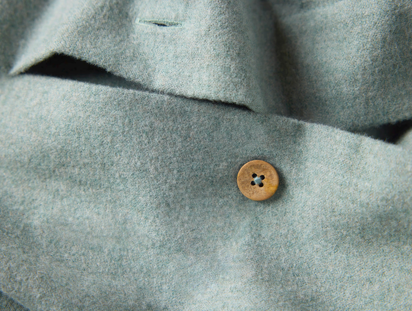 Close-up of wooden button closure on sage Cloud Brushed Flannel duvet cover by Coyuchi.